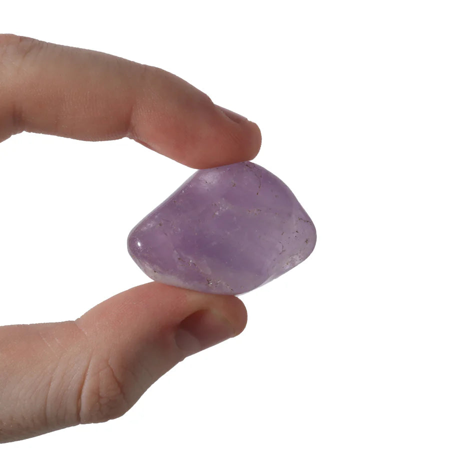 Purple amethyst tumbled stone held in palm showing natural crystal formations