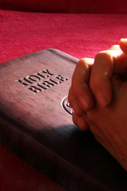 Hands praying over open Bible - the Lord's Prayer