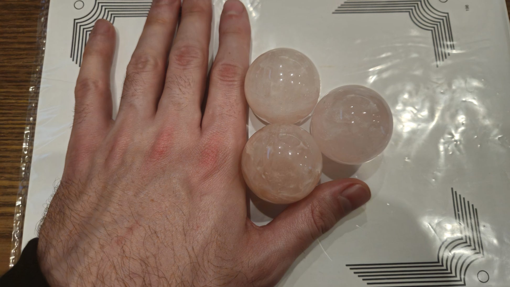 Three 40mm rose quartz spheres in hand showing scale reference