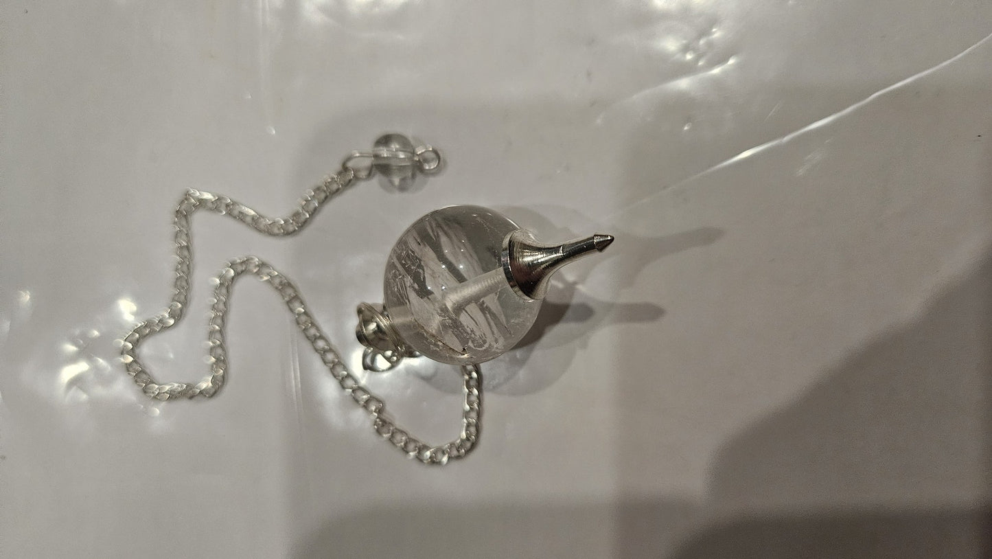Clear quartz ball pendulum detail view with silver cap and chain